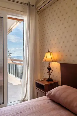a bedroom with a bed and a window with a balcony at Sea view apartment 100m from the beach in Saronida