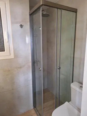a shower with a glass door next to a toilet at Sea view apartment 100m from the beach in Saronida