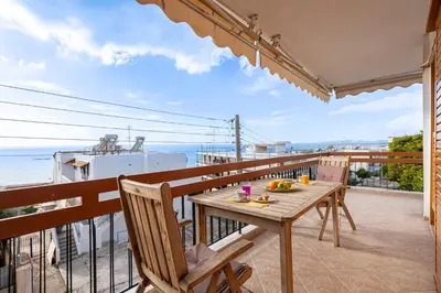 a table on a balcony with a view of the ocean at Sea view apartment 100m from the beach in Saronida
