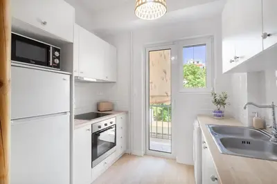 a kitchen with white cabinets and a sink and a window at Modern & Stylish Hideaway Downtown near Acropolis & Metro in Athens