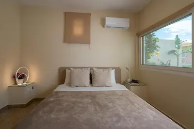 a bedroom with a bed and a large window at Modular Bungalows With Heated Pool Artemis Greece in Artemida