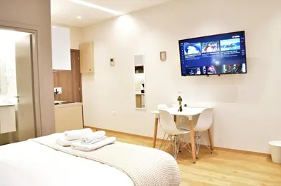 a bedroom with a bed and a table and a tv on the wall at Mood Athens Luxury Apartments and Suites in Athens