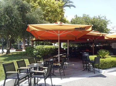 an outdoor patio with tables and chairs and umbrellas at Studio in Kallithea next to Kiprou square in Athens