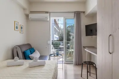 a white bedroom with a bed and a balcony at Elvita Apartments 3 in Athens