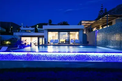 a villa with a swimming pool at night at Black Diamond Luxury Beachfront Villa Selenia in Sounio