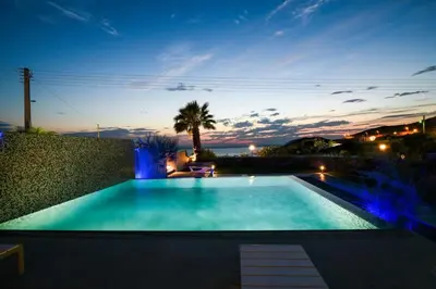 a swimming pool in a backyard at night at Black Diamond Luxury Beachfront Villa Selenia in Sounio