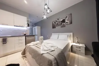 a bedroom with a white bed and a kitchen at AcroView Right In The Center in Athens