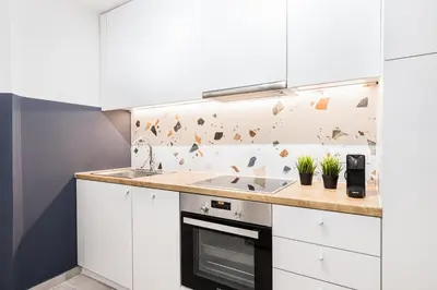 a kitchen with white cabinets and a stove top oven at Serene 1 BR Apartment in Koukaki by UPSTREET in Athens