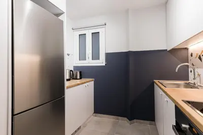 a kitchen with white cabinets and a black refrigerator at Serene 1 BR Apartment in Koukaki by UPSTREET in Athens