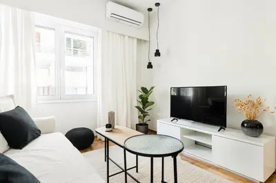 a white living room with a white couch and a tv at Serene 1 BR Apartment in Koukaki by UPSTREET in Athens