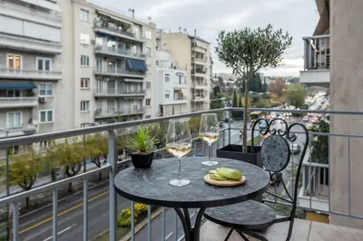 a table with two glasses of wine on a balcony at The Averof (Kalimarmaro) City Center Apartment in Athens