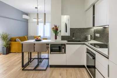 a kitchen with white cabinets and a table with chairs at The Averof (Kalimarmaro) City Center Apartment in Athens