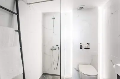a white bathroom with a toilet and a shower at 5BD 2 Level Beachfront Luxury Apt by the Olon in Athens