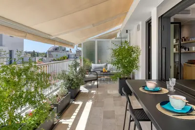 an apartment patio with tables and chairs and a balcony at Central Athens Penthouse in Athens