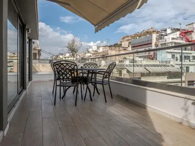 a table and chairs on a balcony with a view at Hestia - Ippokratous 35 in Athens
