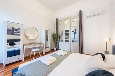 a white bedroom with a bed and a dressing table at Mavrogenous - The Mansion in Athens