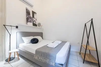 a white bedroom with a bed and a chair at Mavrogenous - The Mansion in Athens