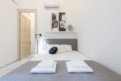 a white bedroom with a bed with two pillows at Mavrogenous - The Mansion in Athens