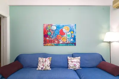 a blue couch with two pillows and a painting on the wall at Venias Two-Bedroom apartment Kallimarmaro and Zappeio area in Athens