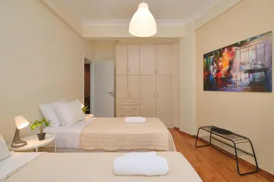 a bedroom with two beds and a painting on the wall at Venias Two-Bedroom apartment Kallimarmaro and Zappeio area in Athens