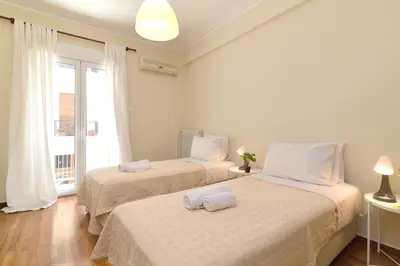 two beds in a white room with a window at Venias Two-Bedroom apartment Kallimarmaro and Zappeio area in Athens