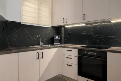 a kitchen with white cabinets and black appliances at Venias Two-Bedroom apartment Kallimarmaro and Zappeio area in Athens