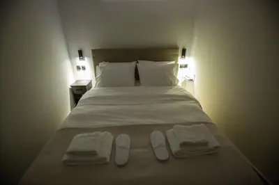 a bedroom with a bed with two pairs of slippers on it at Raise Acropolis View Suites in Athens