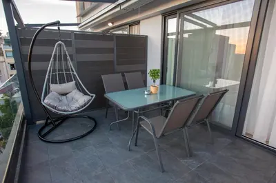 a patio with a swing and a table and chairs at Raise Acropolis View Suites in Athens
