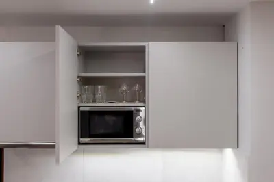 a kitchen with a microwave in a white kitchen at Koios Apartments in Athens