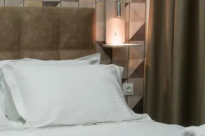 a bed with a white pillow and a lamp at Koios Apartments in Athens