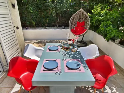 a table with red chairs and a blue table with wine glasses at Five Seasons Alimos in Athens