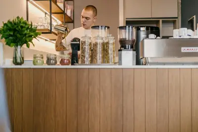 a man standing behind a counter in a kitchen at Cohort Koukaki in Athens