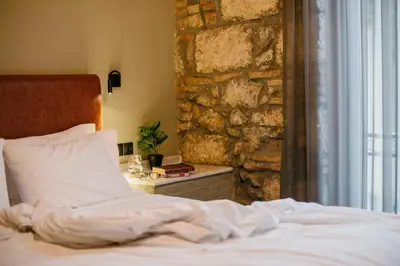 a bedroom with a bed and a stone wall at Cohort Koukaki in Athens