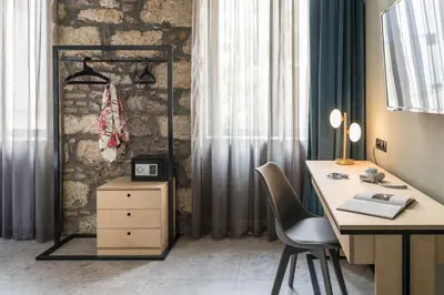 an office with a desk and a chair next to a stone wall at Cohort Koukaki in Athens