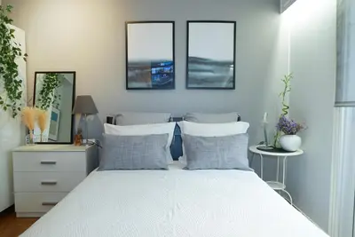 a bedroom with a white bed with three windows at Comfy studio apartment very close to city centre in Athens