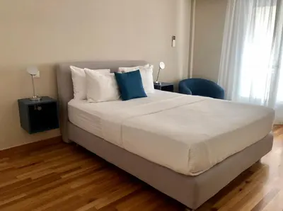 a bedroom with a large bed with white sheets and blue pillows at 2 Bedroom Acropolis Apartment in Athens