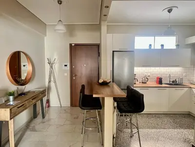 a kitchen with a wooden table and bar stools at 2 Bedroom Acropolis Apartment in Athens