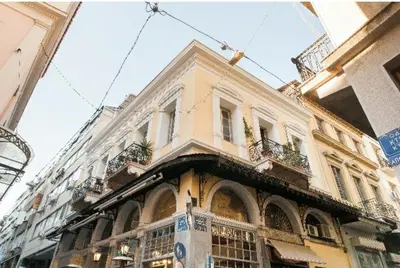 a large yellow building with windows and plants on it at The monumental house in Athens