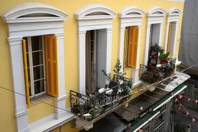 a yellow building with windows and plants on a balcony at The monumental house in Athens