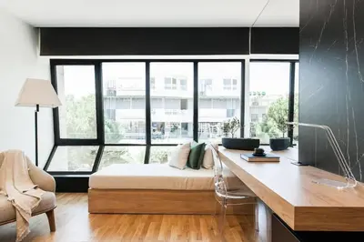 a bedroom with a bed and a desk in front of a window at 2 SidebySide Suites in Athens Riviera by The Olon in Athens
