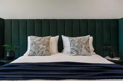 a large bed with a green headboard and pillows at 2 SidebySide Suites in Athens Riviera by The Olon in Athens