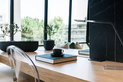 a desk with a book and a cup and a lamp at 2 SidebySide Suites in Athens Riviera by The Olon in Athens
