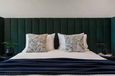 a large bed with a green headboard and pillows at 2 SidebySide Suites in Athens Riviera by The Olon in Athens