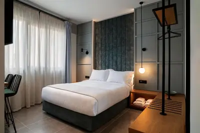 a hotel room with a large bed and a desk at Bob W Athens Akadimia in Athens
