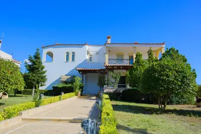 a large white house with a driveway at GREEN PARADISE PALAIA FoKAIA in Áyios Yeóryios