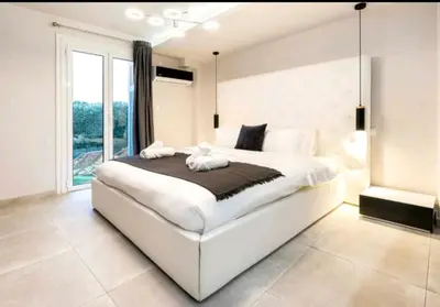 a bedroom with a large white bed and a window at DELUXE ROMANTIC JACUZZI in Athens