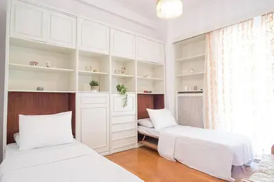 two beds in a room with white cabinets and a window at Spacious and Luxurious Apart Athens Center by MPS in Athens