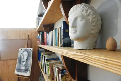 a bust of a head on a shelf with books at Unique - Spacious Studio with rooftop / Thissio in Athens