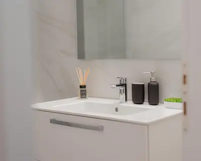 a white bathroom with a sink and a mirror at Kolonaki Luxury Residence in Athens