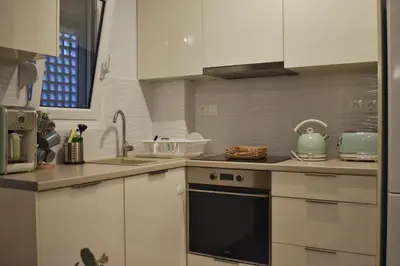 a kitchen with white cabinets and a stove top oven at Window to...Acropolis! in Athens